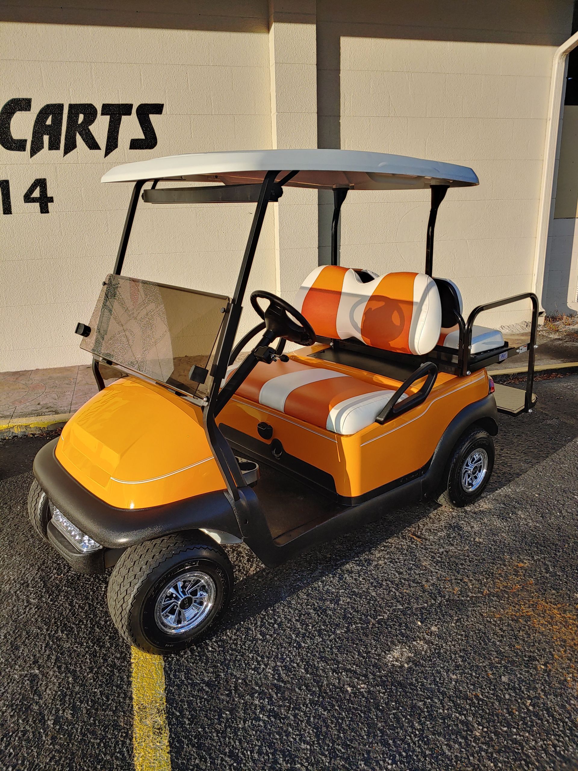 Yellow and white golf cart parked outside a business with 