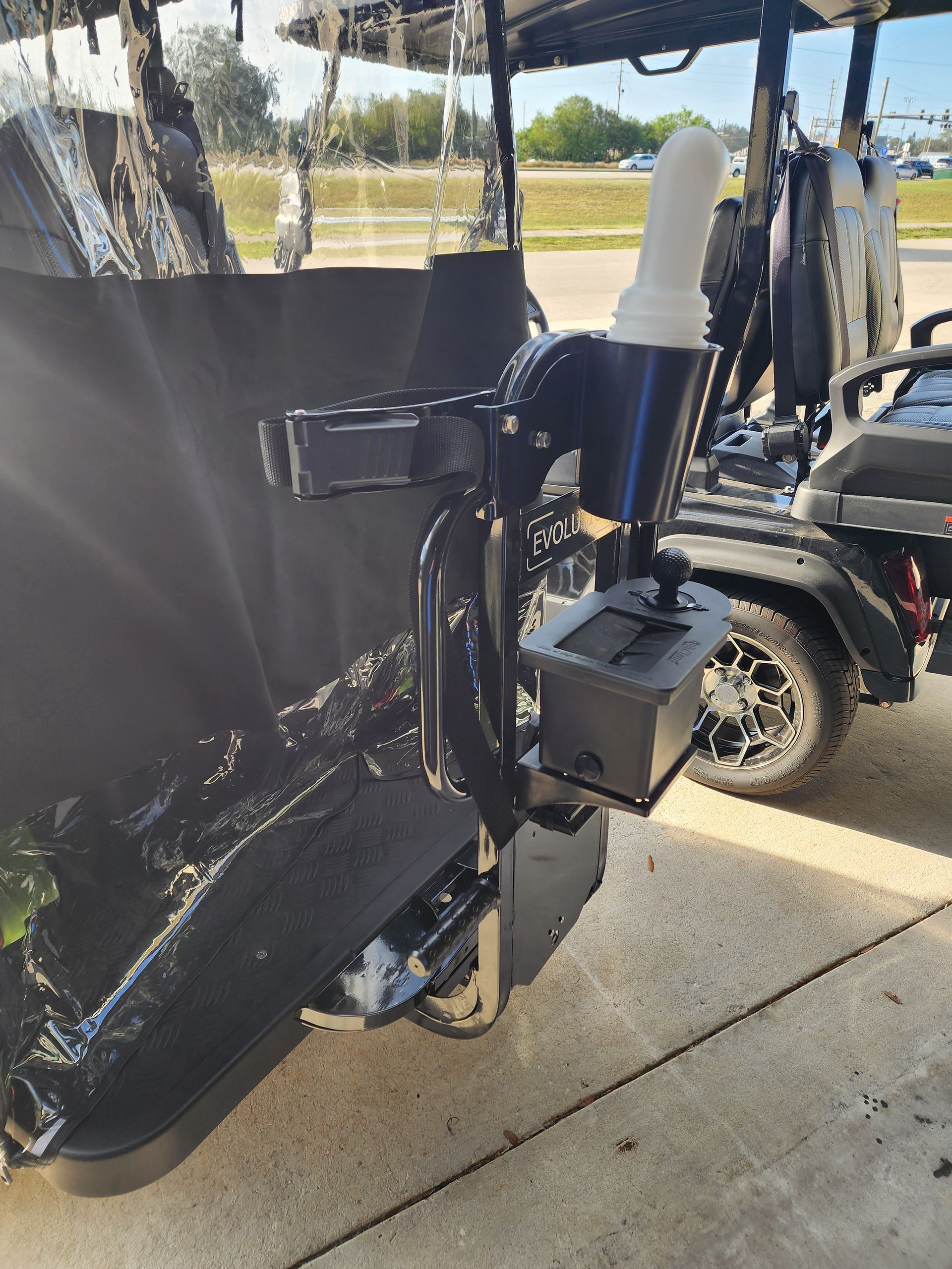 Black golf cart with mounted white object and black controls.