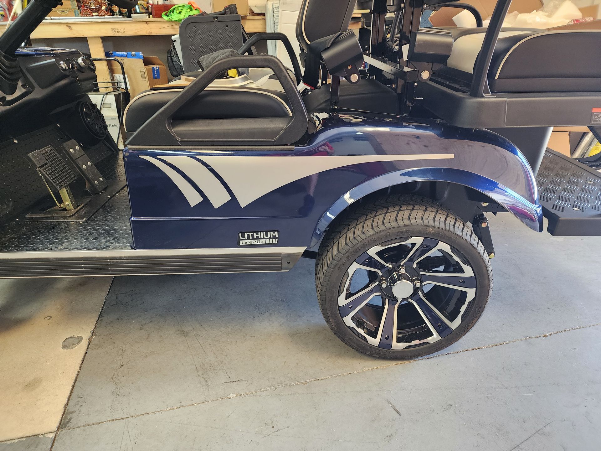 Blue golf cart with custom wheels, parked indoors.