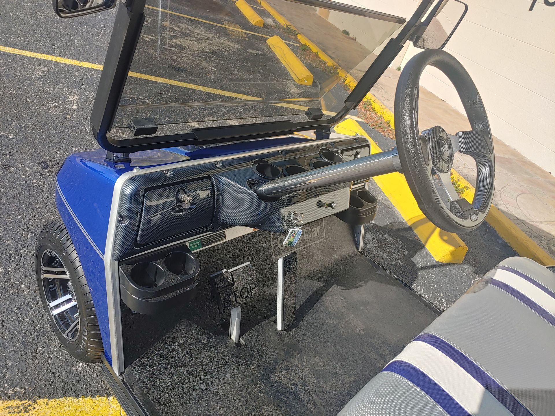 Blue golf cart interior with steering wheel, cup holders, and black dashboard.