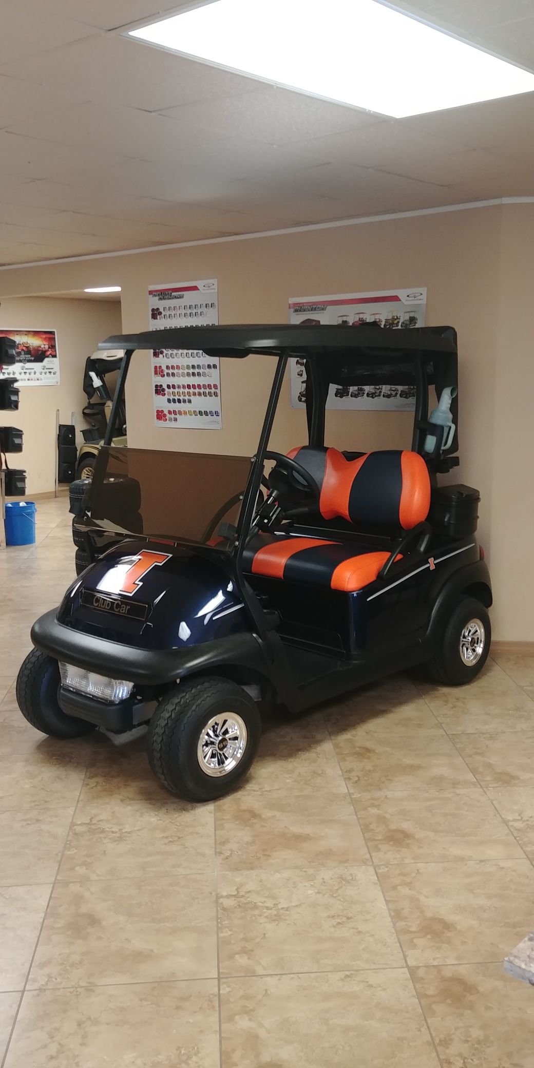 A navy blue and orange golf cart parked inside a room.