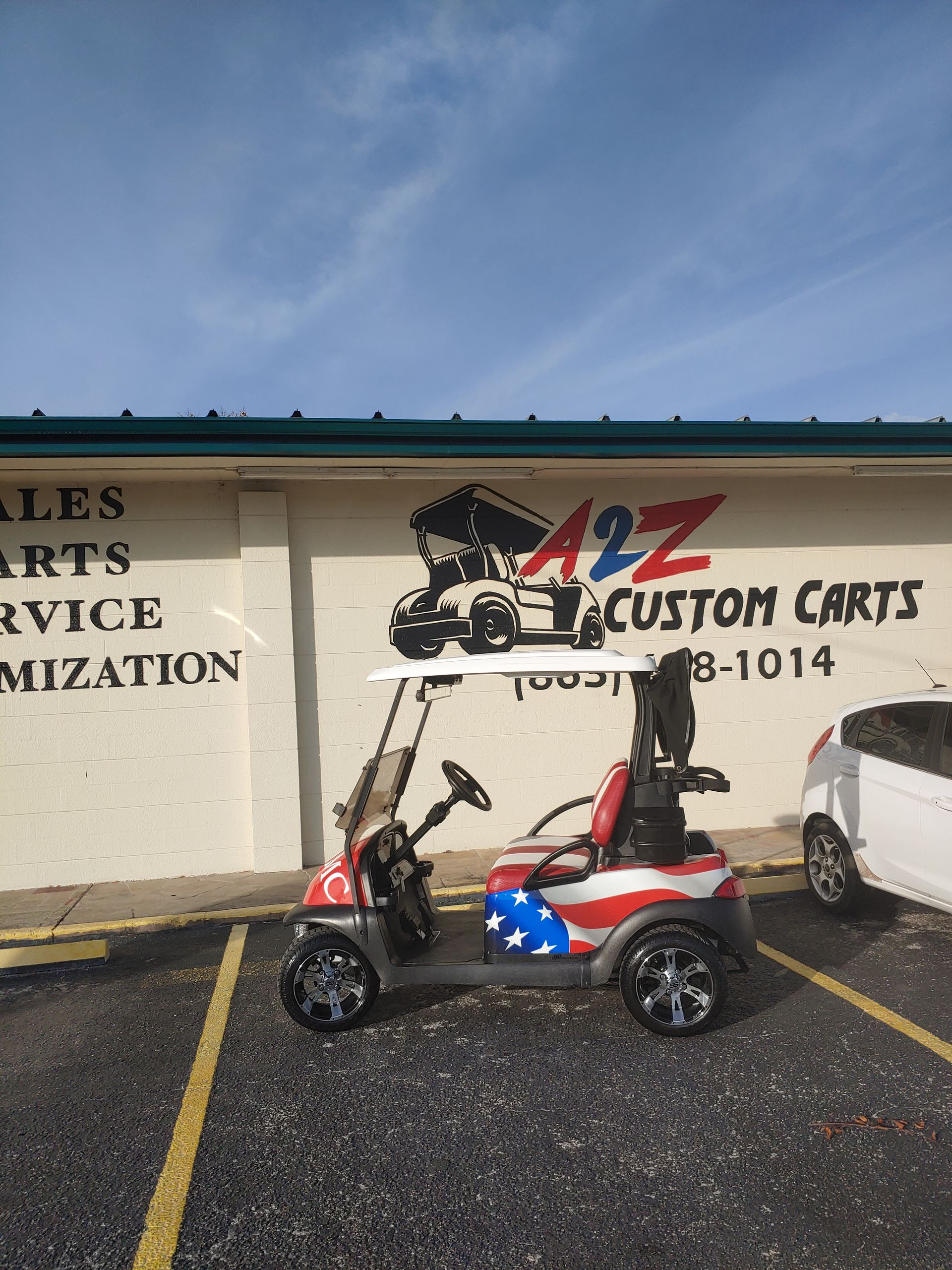 Red, white, and blue custom golf cart parked in front of A to Z Custom Carts building.