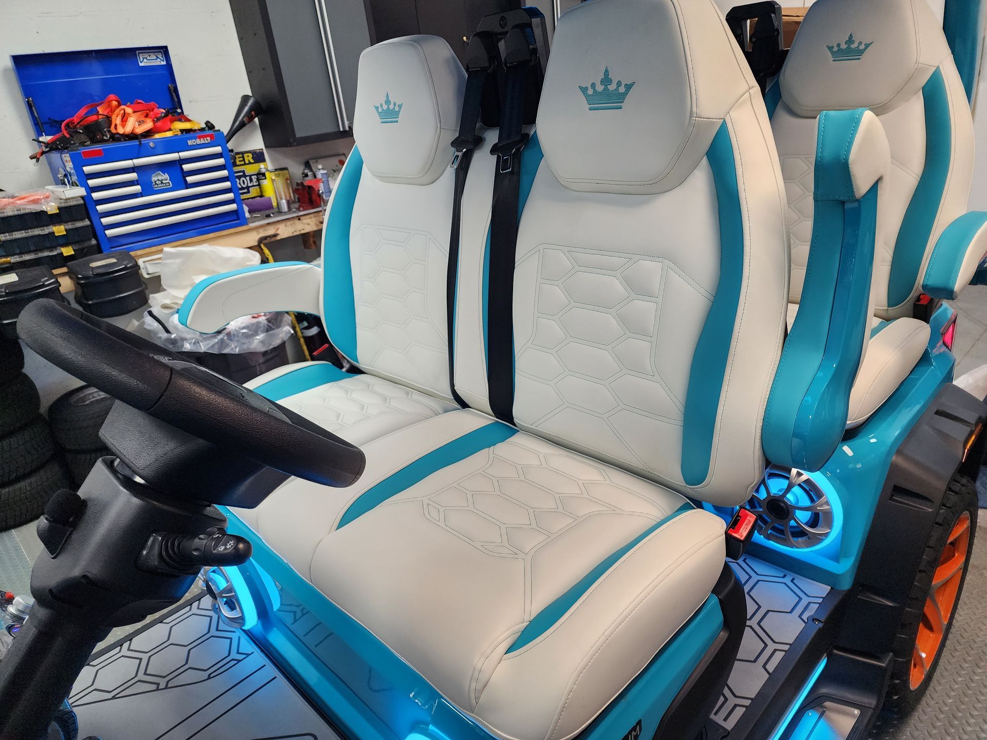 White and teal custom golf cart seats in a garage.