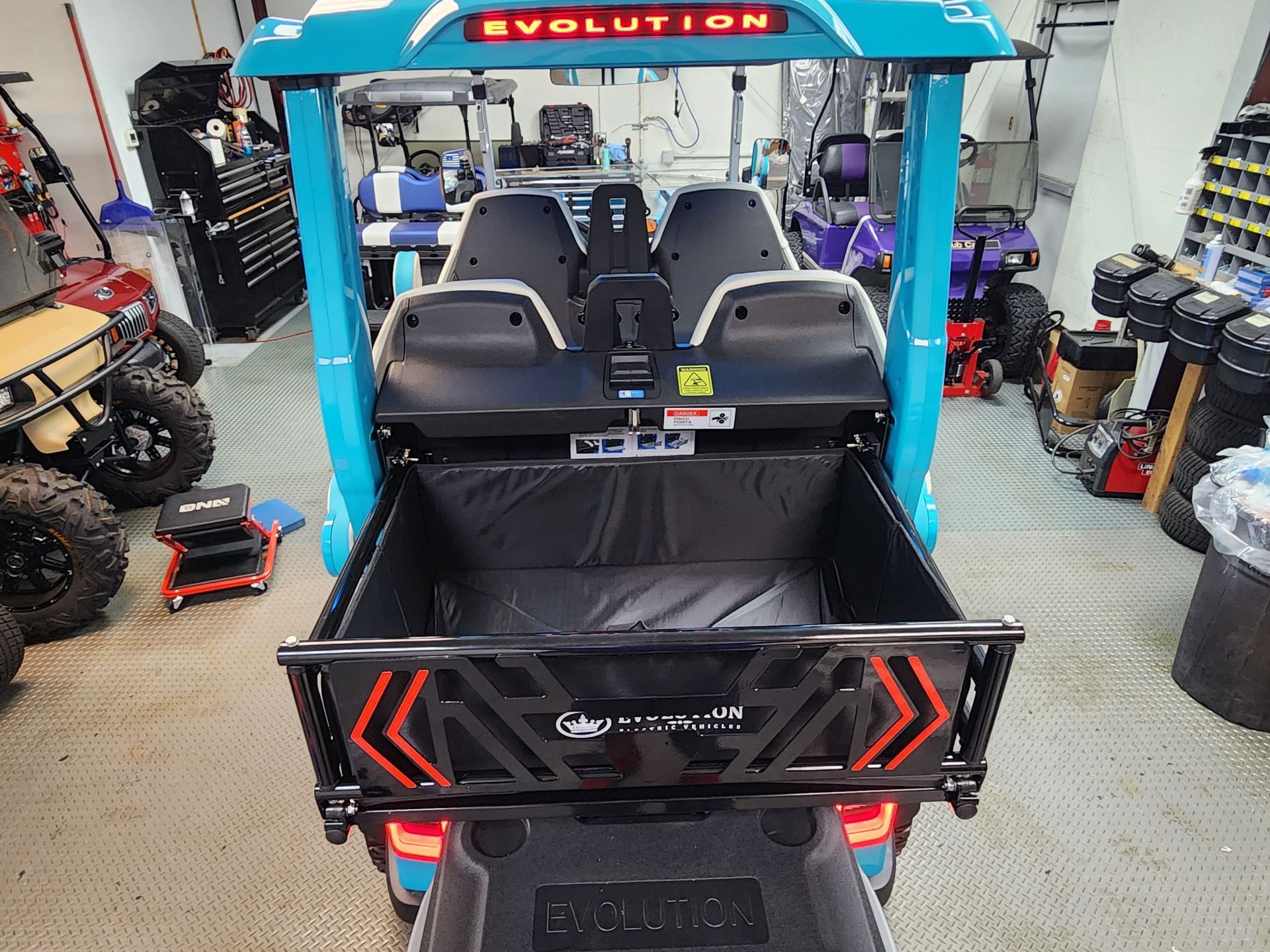 Blue and black Evolution golf cart with cargo bed. Rear view in a garage.