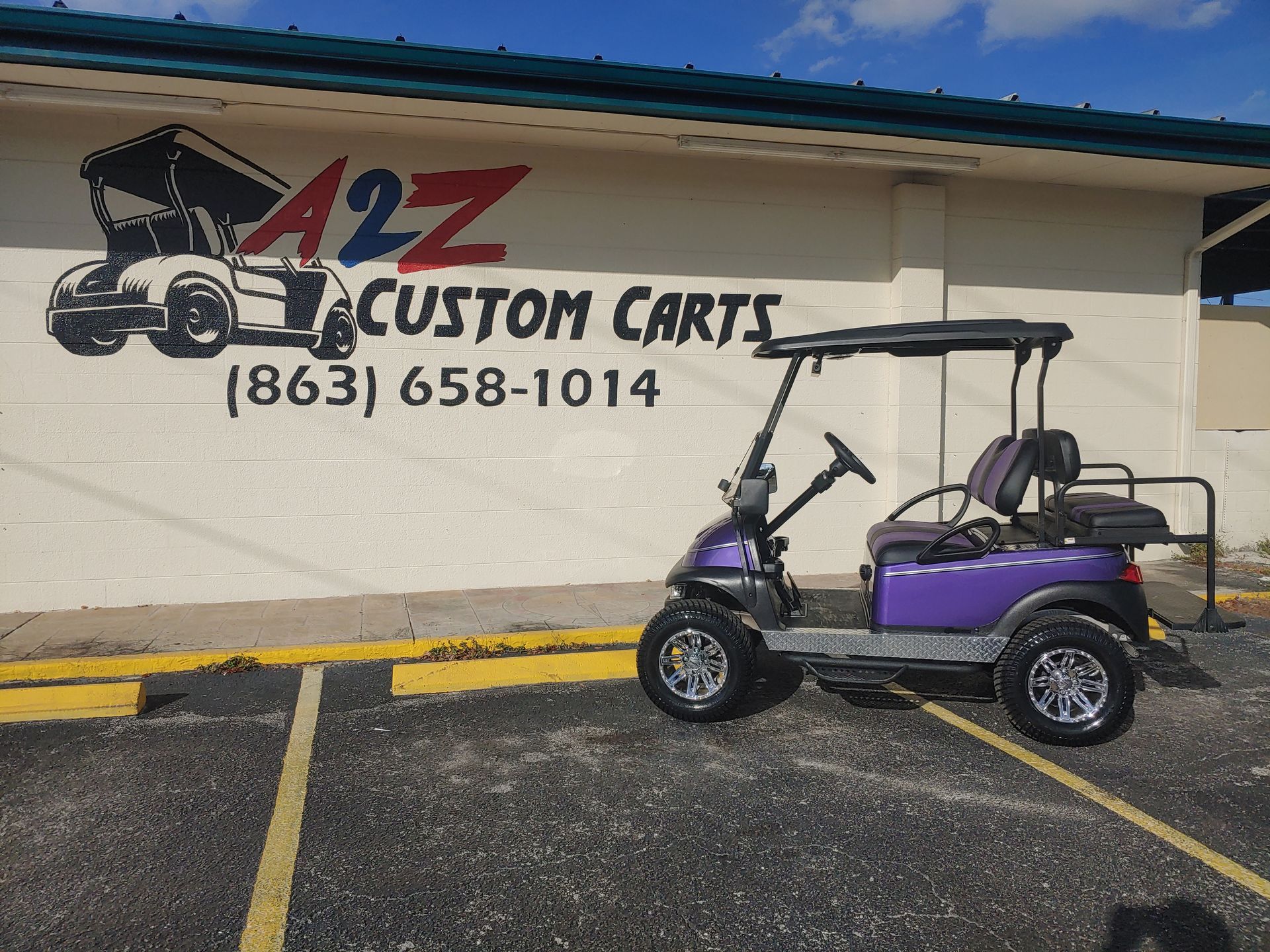 Purple custom golf cart parked in front of A2Z Custom Carts building; phone number (863) 658-1014 visible.