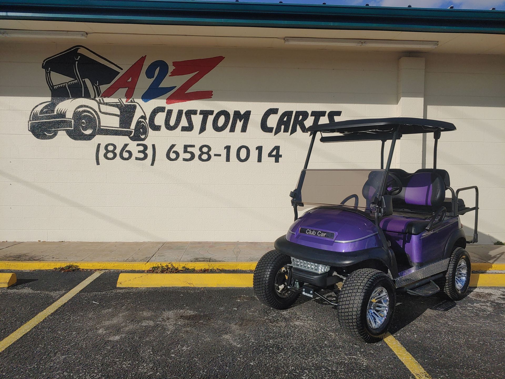Purple golf cart parked in front of A2Z Custom Carts storefront; (863) 658-1014.