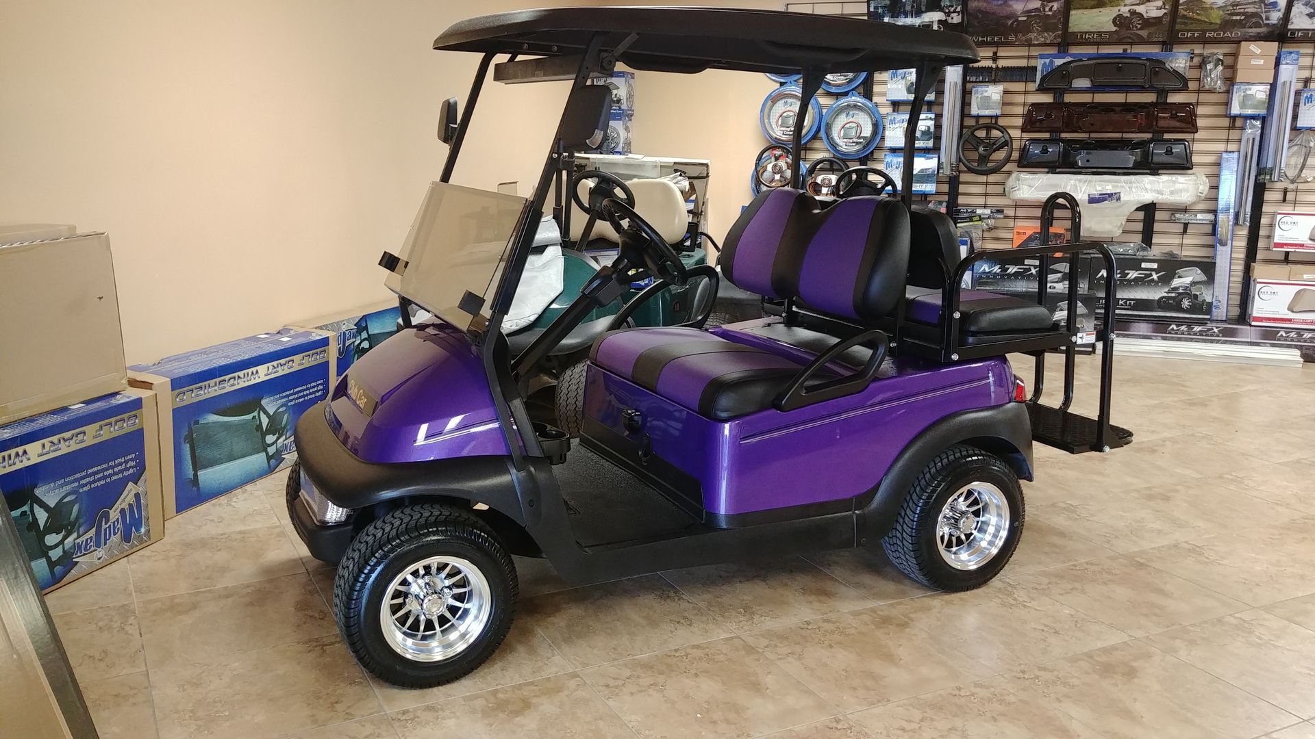 Purple golf cart with black roof and seats, indoors.
