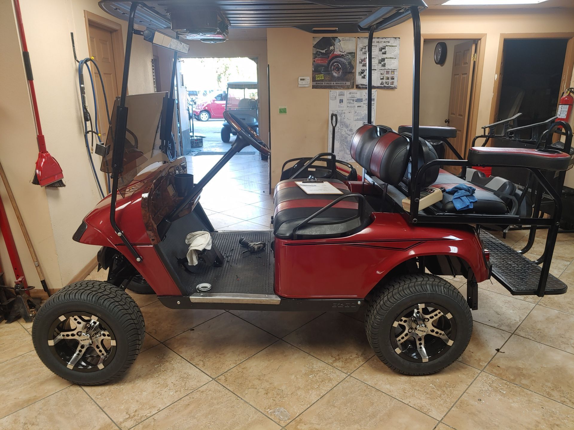 Red golf cart with black accents, large tires, and lift kit parked in a garage.
