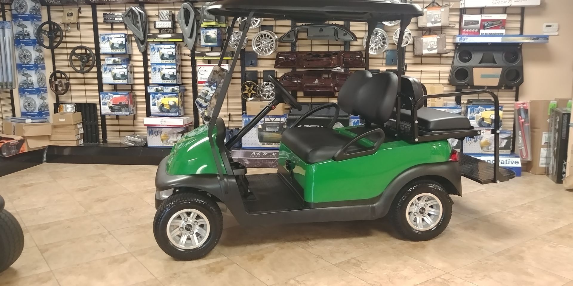 Green golf cart in a store, with black seats and a black roof.