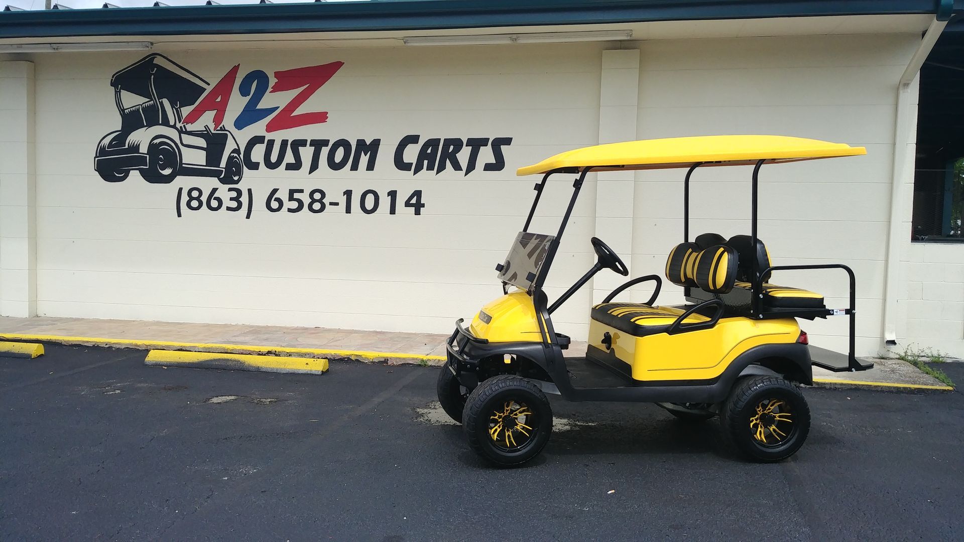 Yellow custom golf cart parked in front of A2Z Custom Carts building.