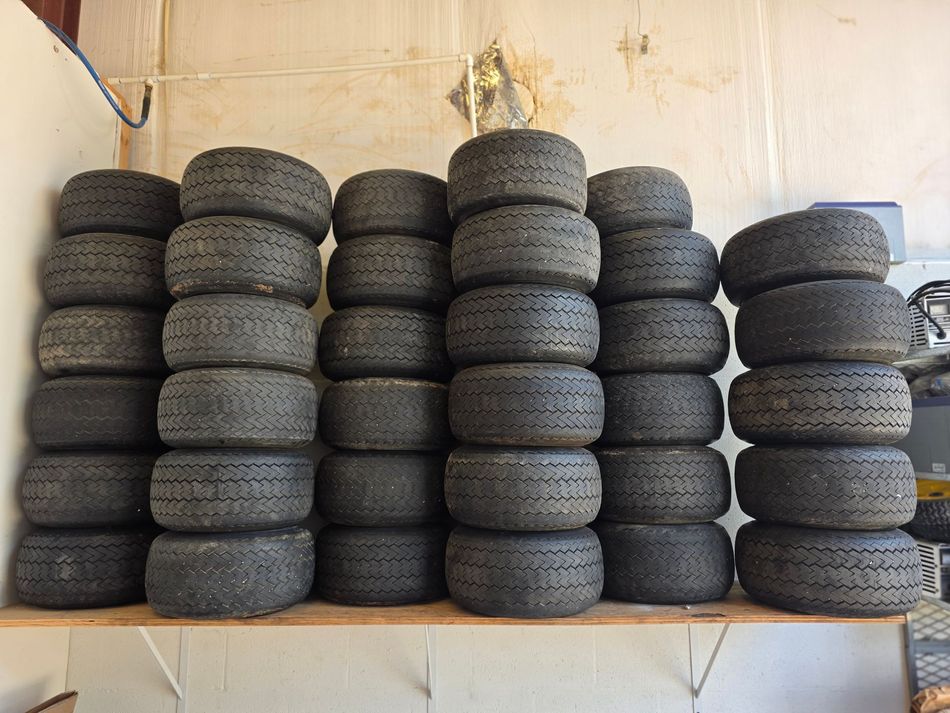 Stacks of used black car tires piled on shelves in a warehouse-like room