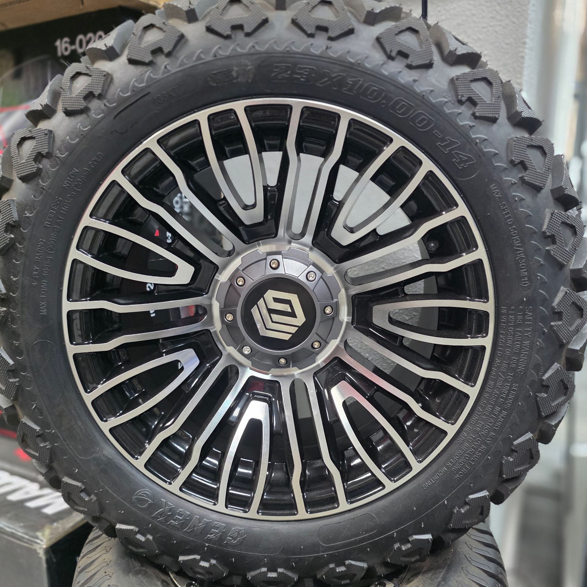 Black off-road tire with chrome-accented wheel on a vehicle outdoors.