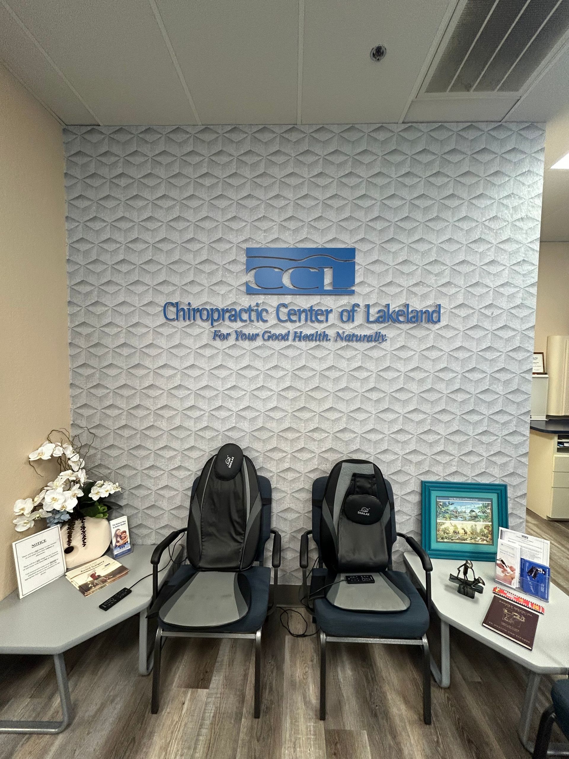 A waiting room with chairs , tables and a sign that says chiropractic center of lakeland.