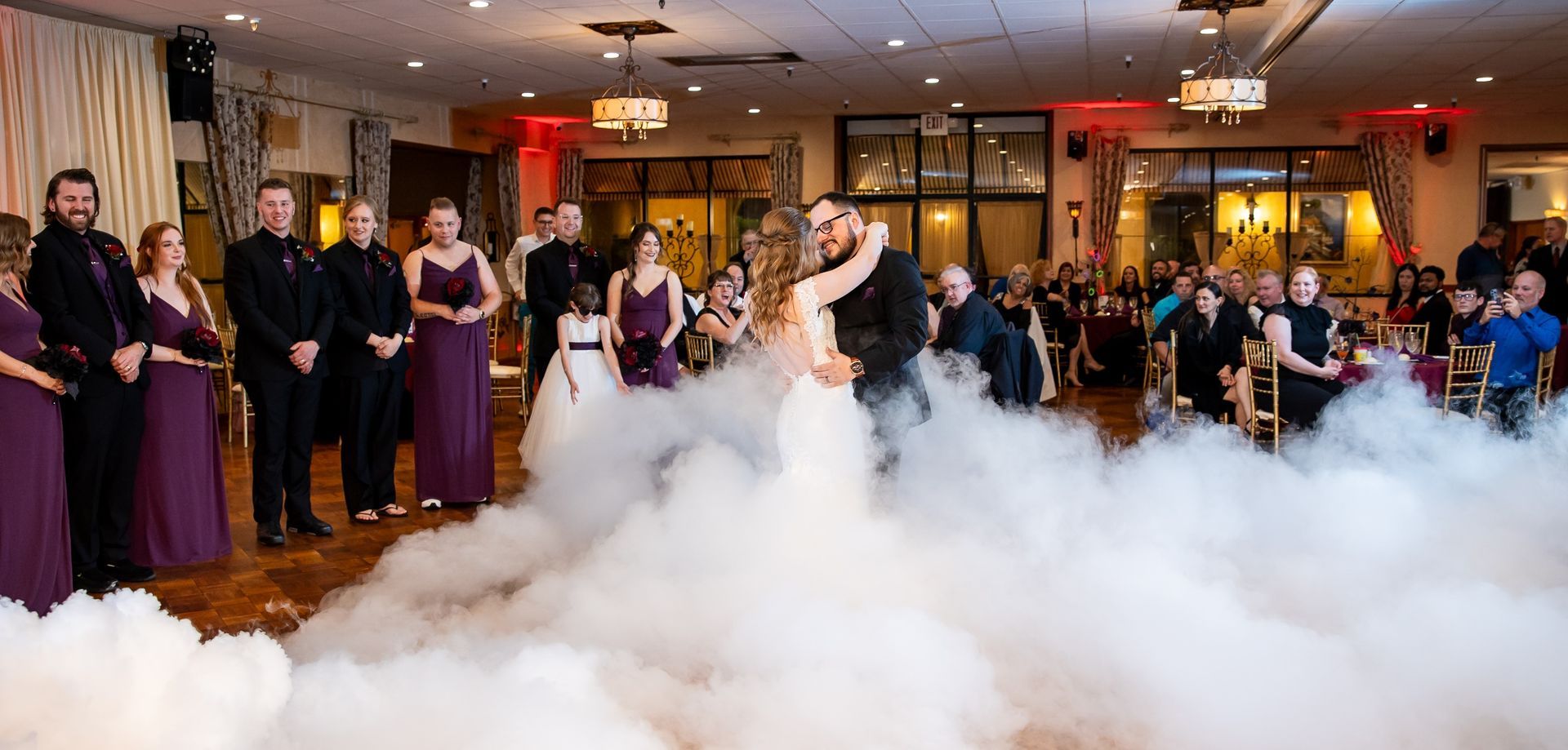 A bride and groom are dancing in a room surrounded by smoke.