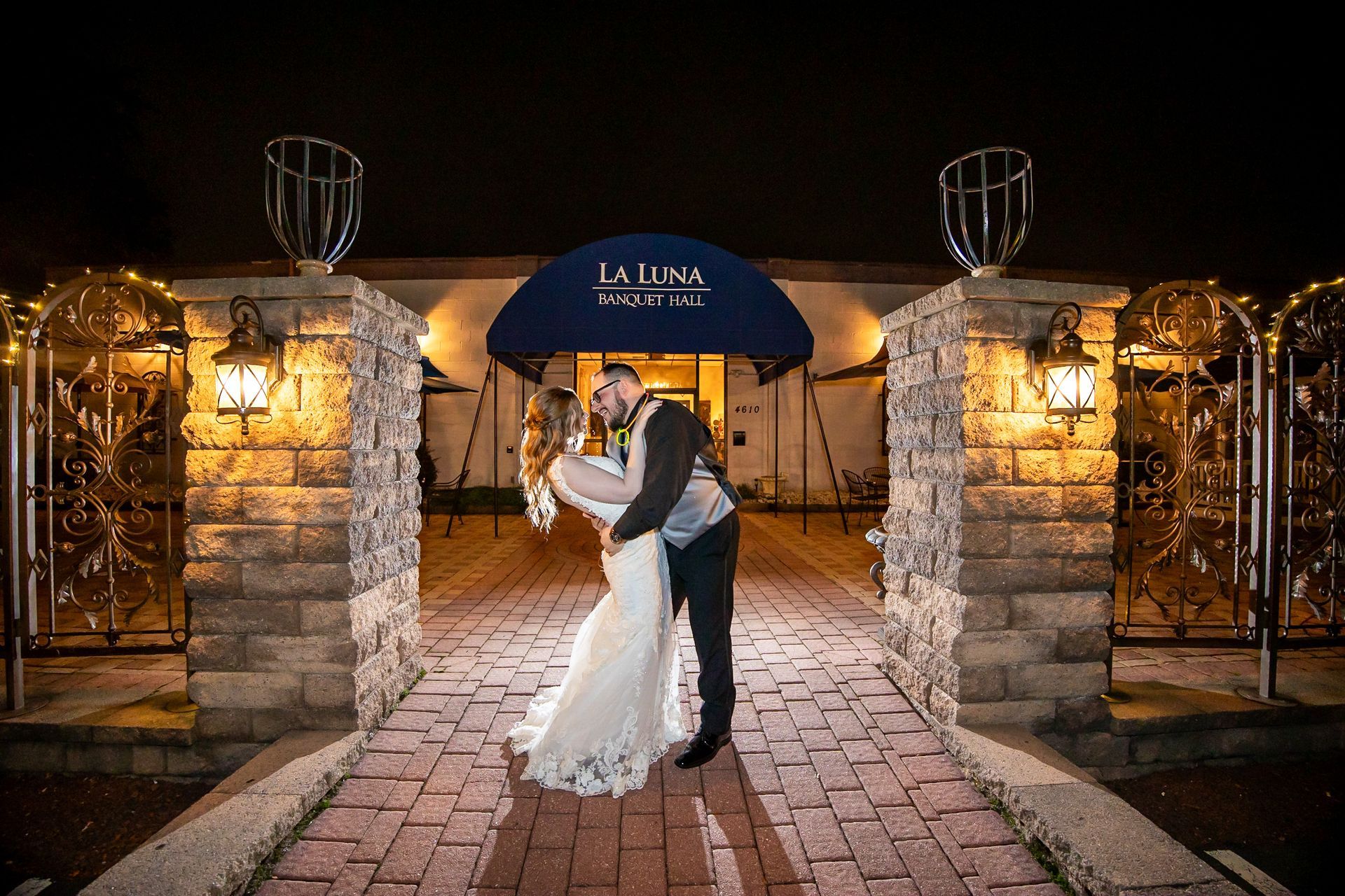 A bride and groom are kissing in front of a building at night.