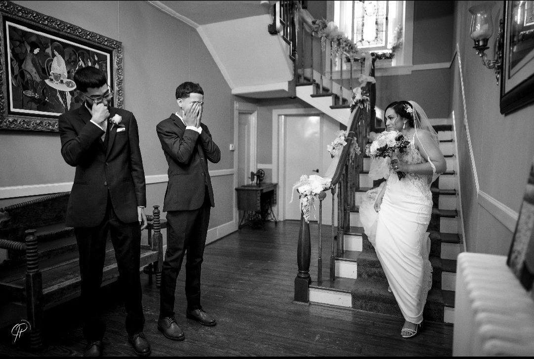 A black and white photo of a bride and groom standing in a hallway.