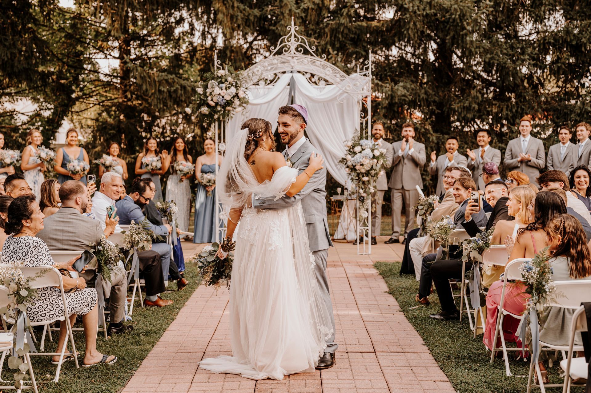 A bride and groom are dancing at their wedding ceremony in front of their wedding guests.
