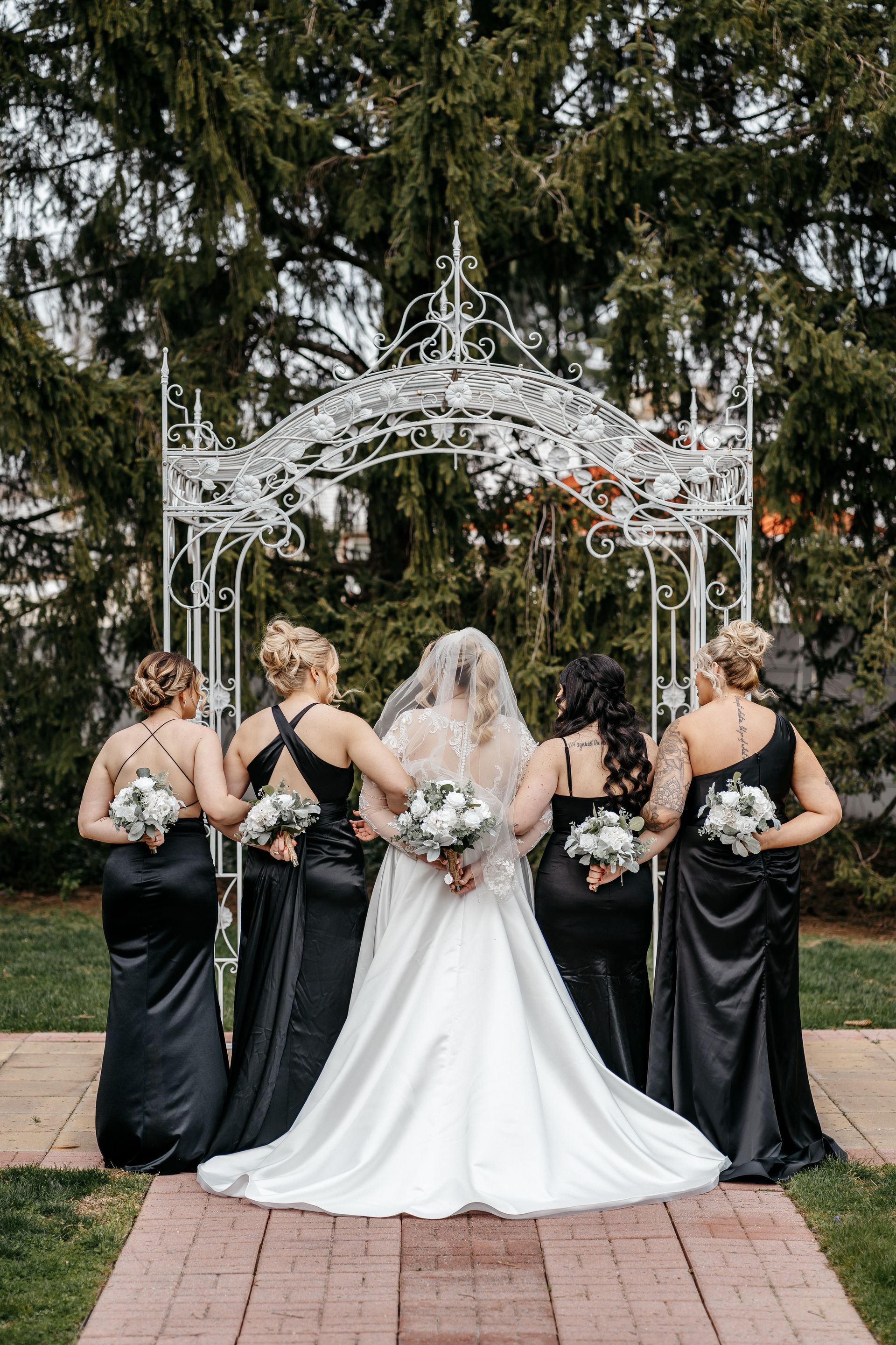 A bride and her bridesmaids are posing for a picture in front of a white archway.