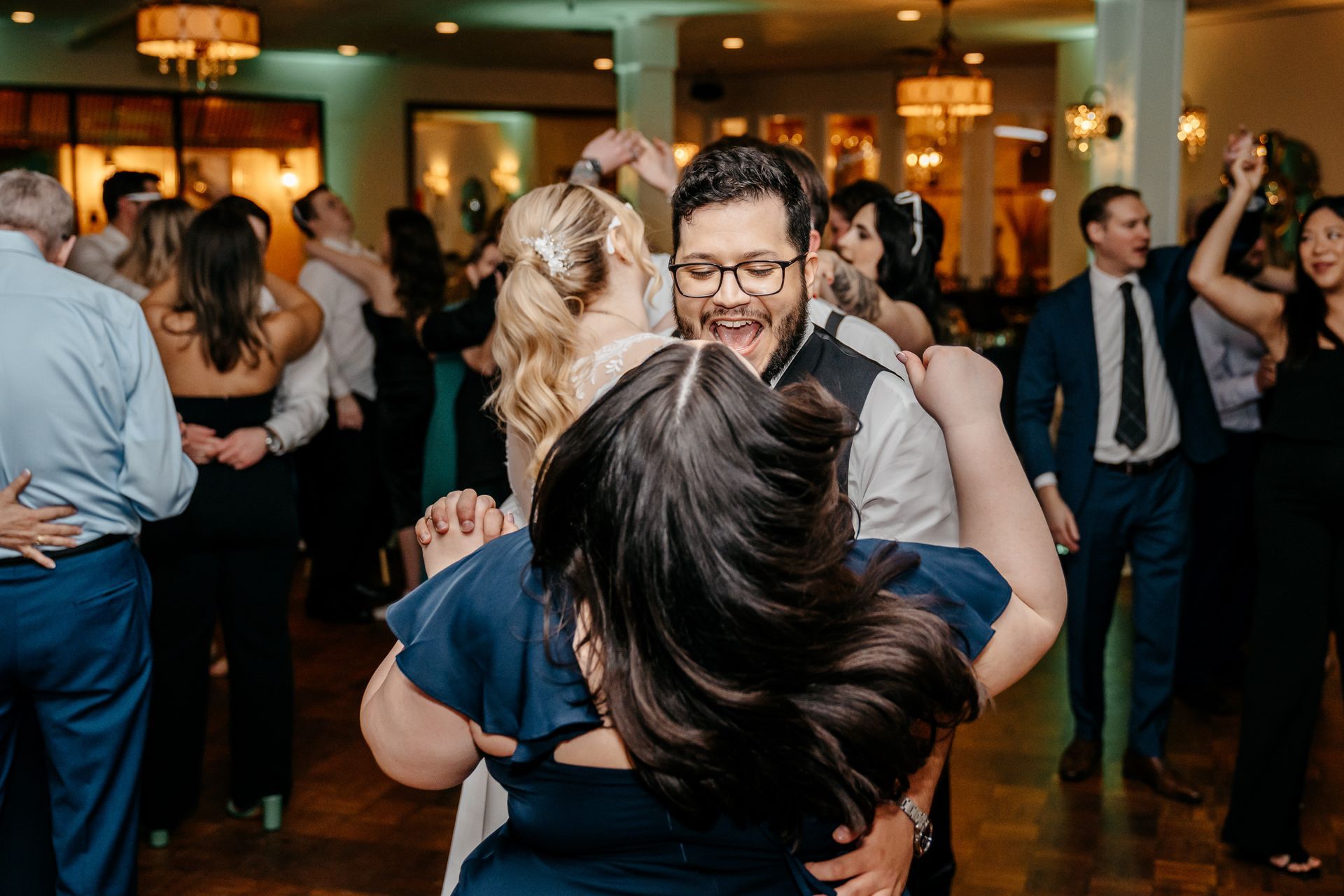 A group of people are dancing together at a wedding reception.
