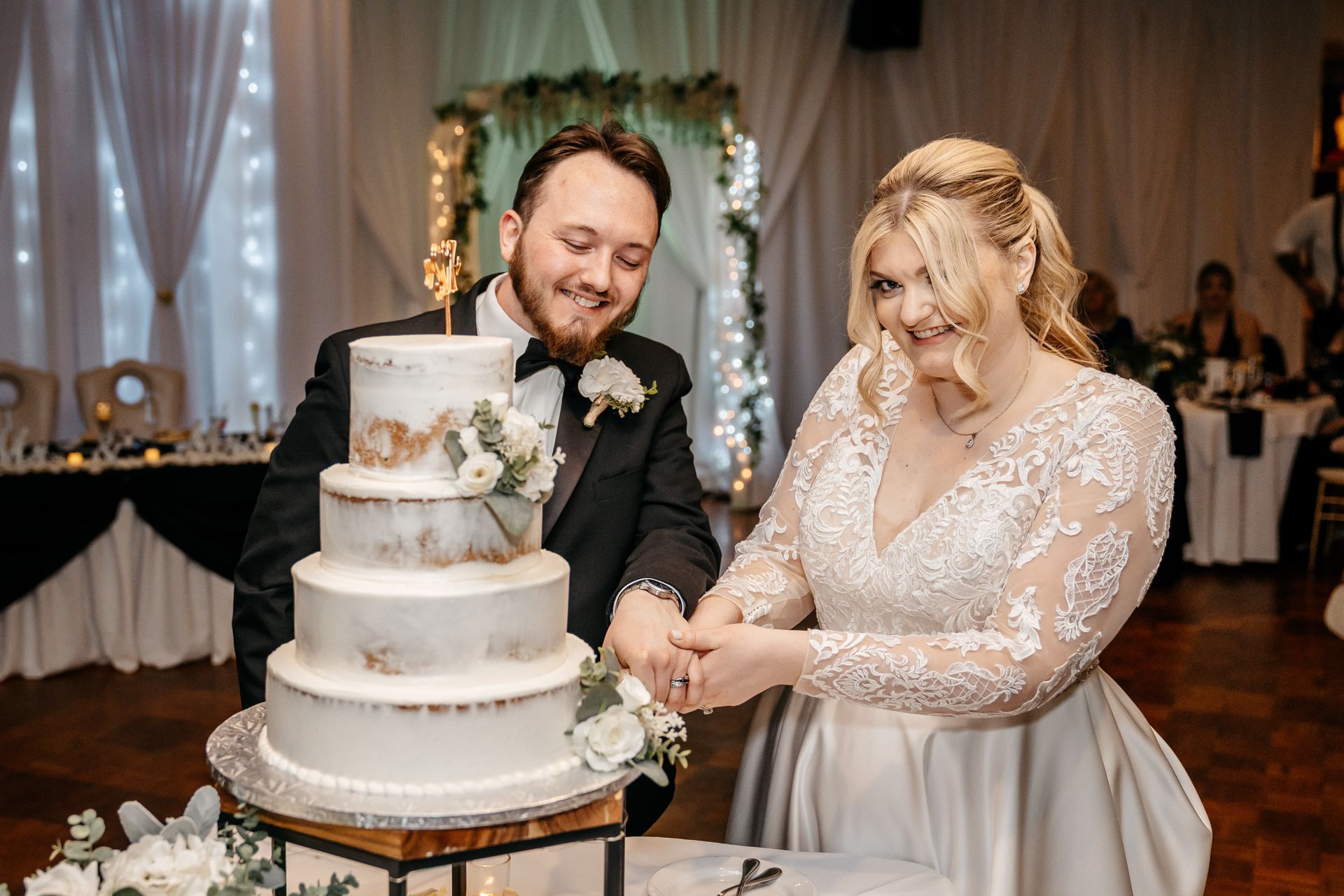 A bride and groom are cutting their wedding cake together.