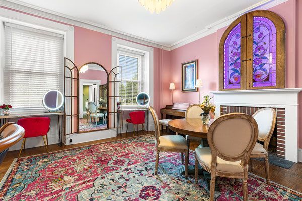 A living room with pink walls , a fireplace , a table and chairs.