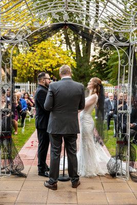 A bride and groom are getting married under a gazebo.