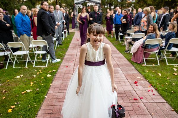 A flower girl is walking down the aisle at a wedding.