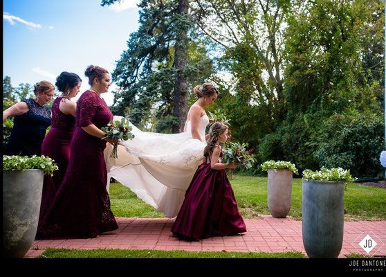 A bride and her bridesmaids are walking down a brick walkway.