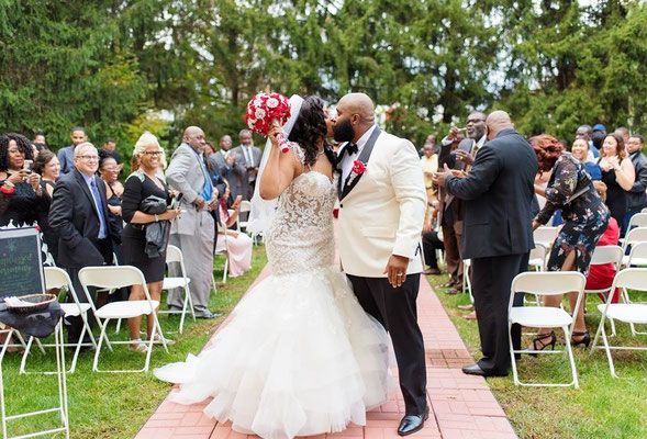 A bride and groom are kissing while walking down the aisle at their wedding.