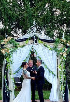 A bride and groom are getting married under a gazebo.