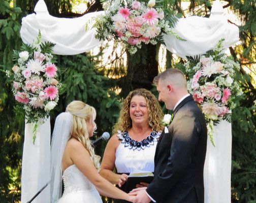 A bride and groom are holding hands during their wedding ceremony