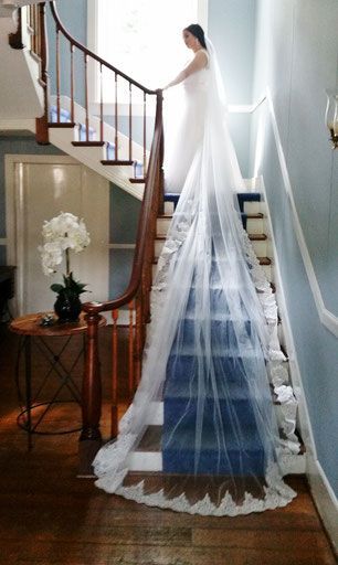 A bride in a wedding dress and veil is standing on a set of stairs.