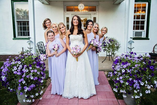 A bride and her bridesmaids are posing for a picture in front of a house.