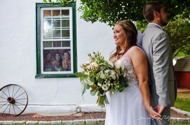 A bride and groom are posing for a picture in front of a white building.