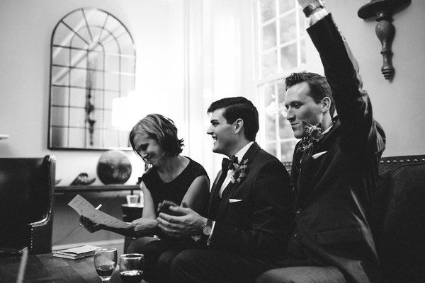 A group of people are sitting on a couch with their arms in the air.