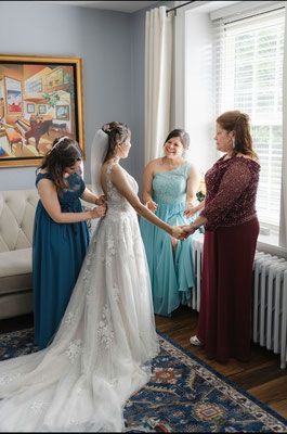 A bride and her bridesmaids are holding hands in a room.