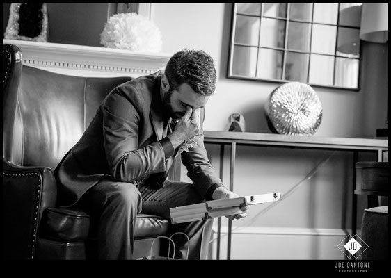 A man in a suit is sitting in a chair reading a book