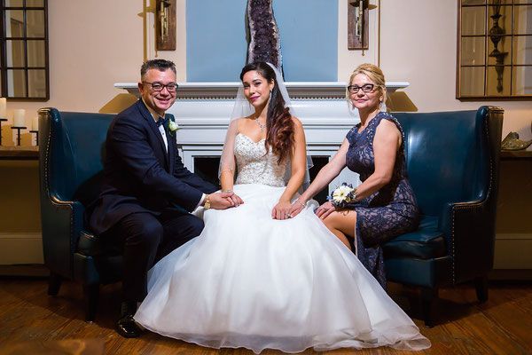 A bride and groom are posing for a picture with their parents.