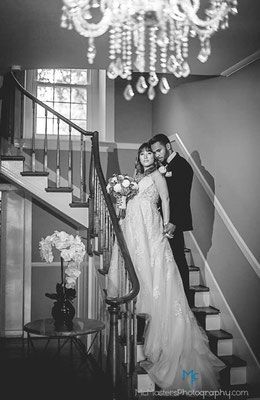 A bride and groom are posing for a picture on a set of stairs.