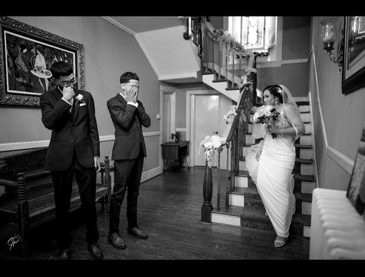 A black and white photo of a bride and groom walking down the stairs.
