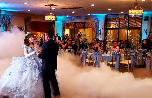 A man and a woman are dancing in a ballroom with smoke coming out of the ceiling.