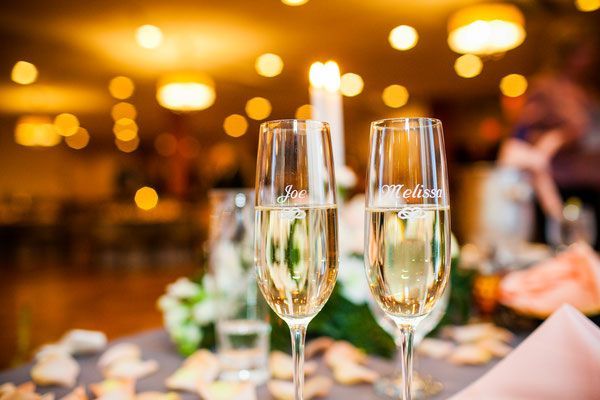 Two glasses of champagne are on a table at a wedding reception.