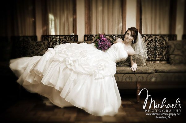 A bride in a wedding dress is laying on a couch