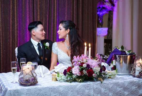 A bride and groom are sitting at a table at a wedding reception.