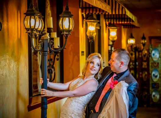 A bride and groom are posing for a picture in front of a street light.
