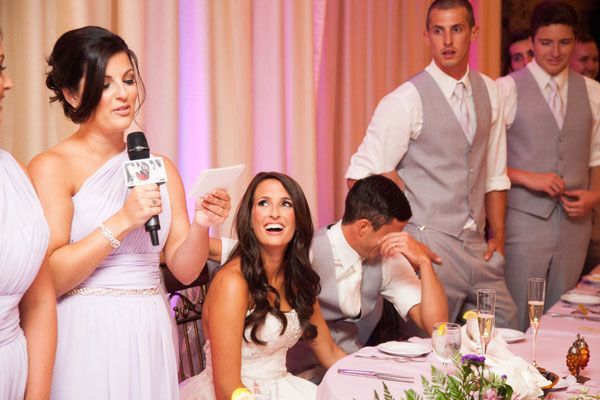 A woman is giving a speech to a bride and groom at a wedding reception.