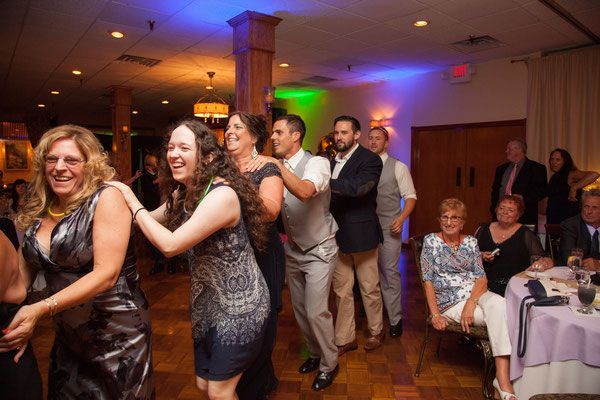 A group of people are dancing in a room at a wedding reception.