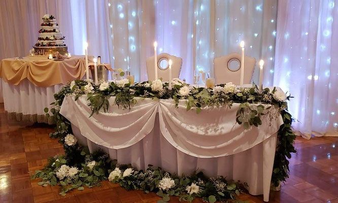 A couple 's table is decorated with flowers and candles for a wedding reception.