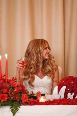 A bride is sitting at a table with a glass of wine.
