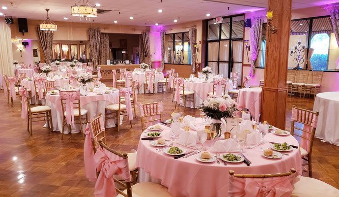 A large room with tables and chairs set up for a wedding reception.